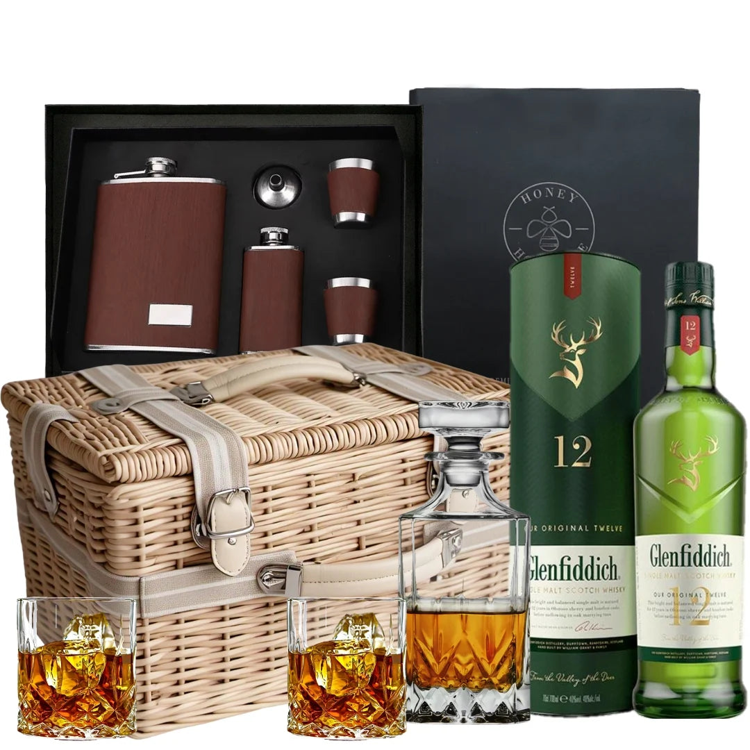 Glenfiddich whisky set with wicker hamper, glasses, and flasks on a white background