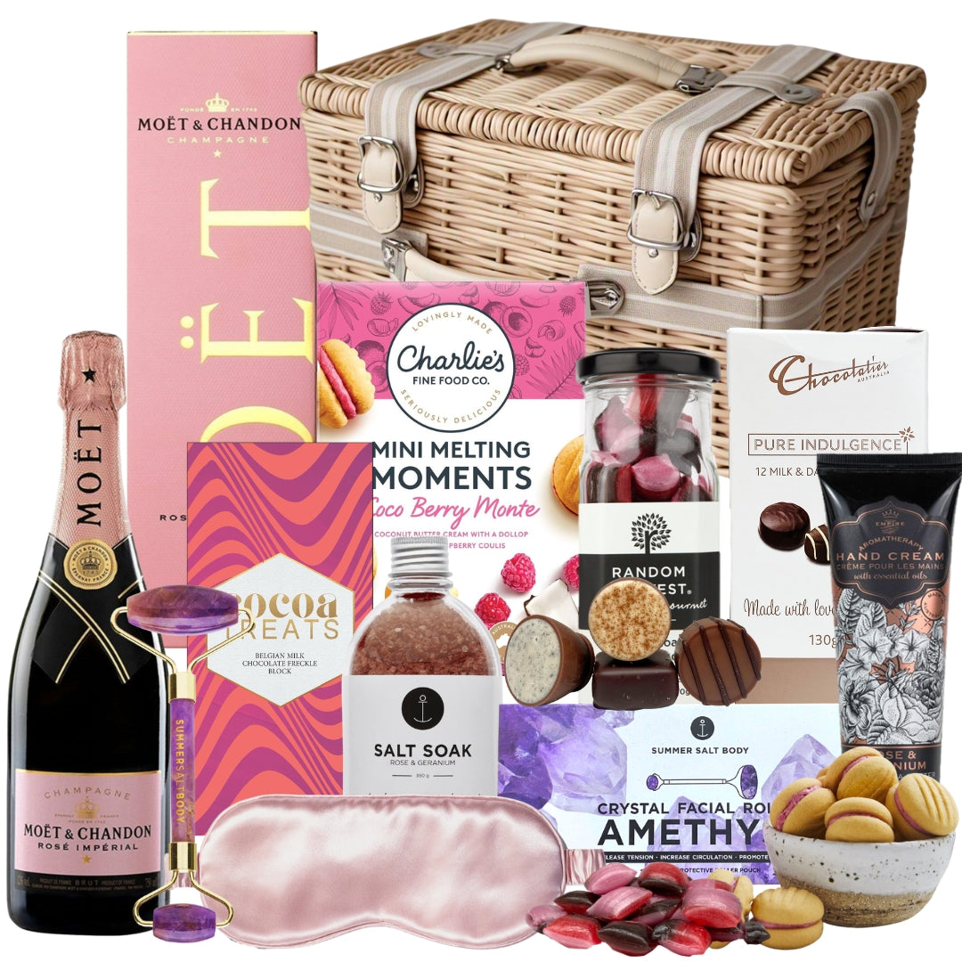 Gourmet gift basket with champagne, chocolates, and other treats on a white background