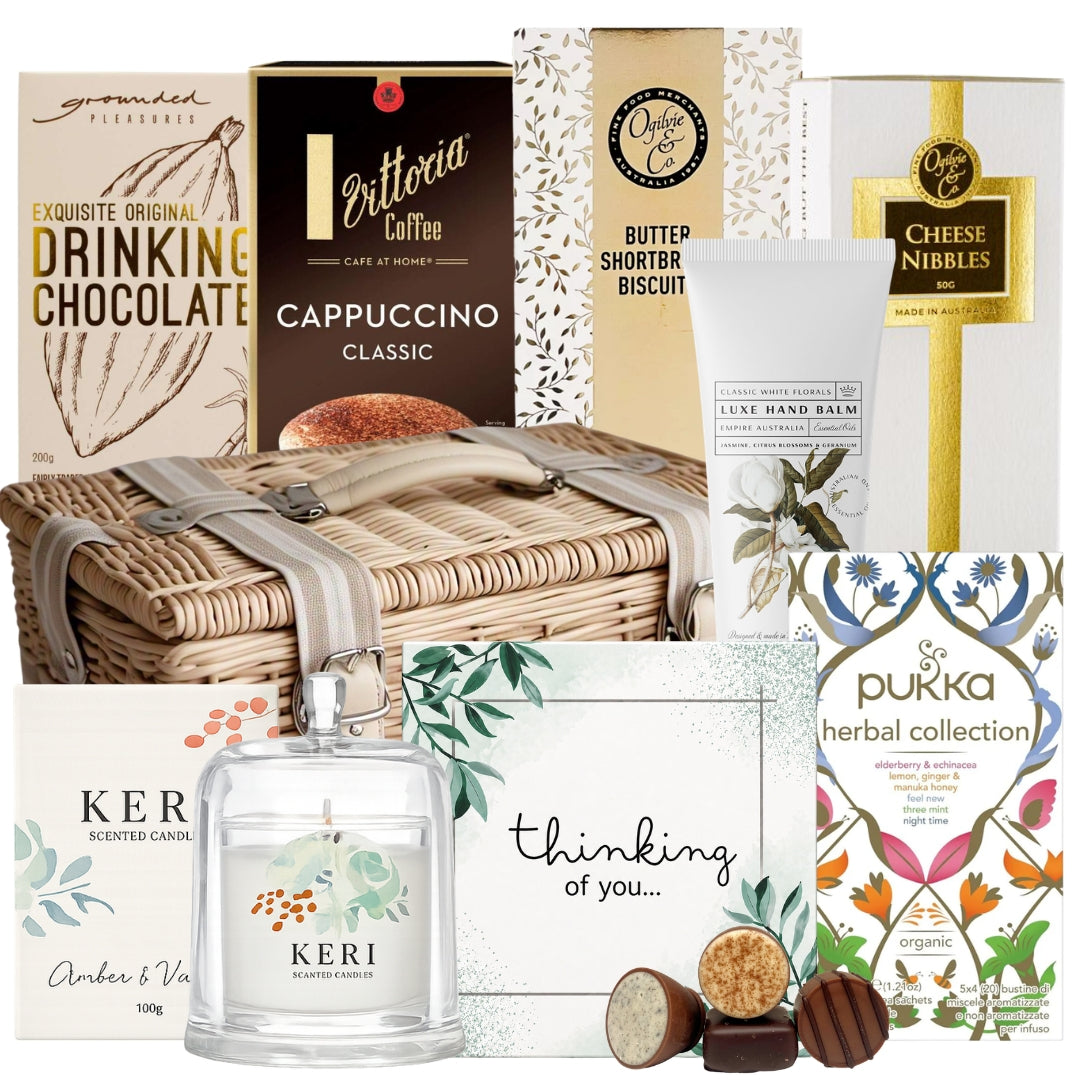 Sympathy food basket featuring herbal tea, drinking chocolate, coffee sachets, biscuits, hand balm, a scented candle, and chocolates