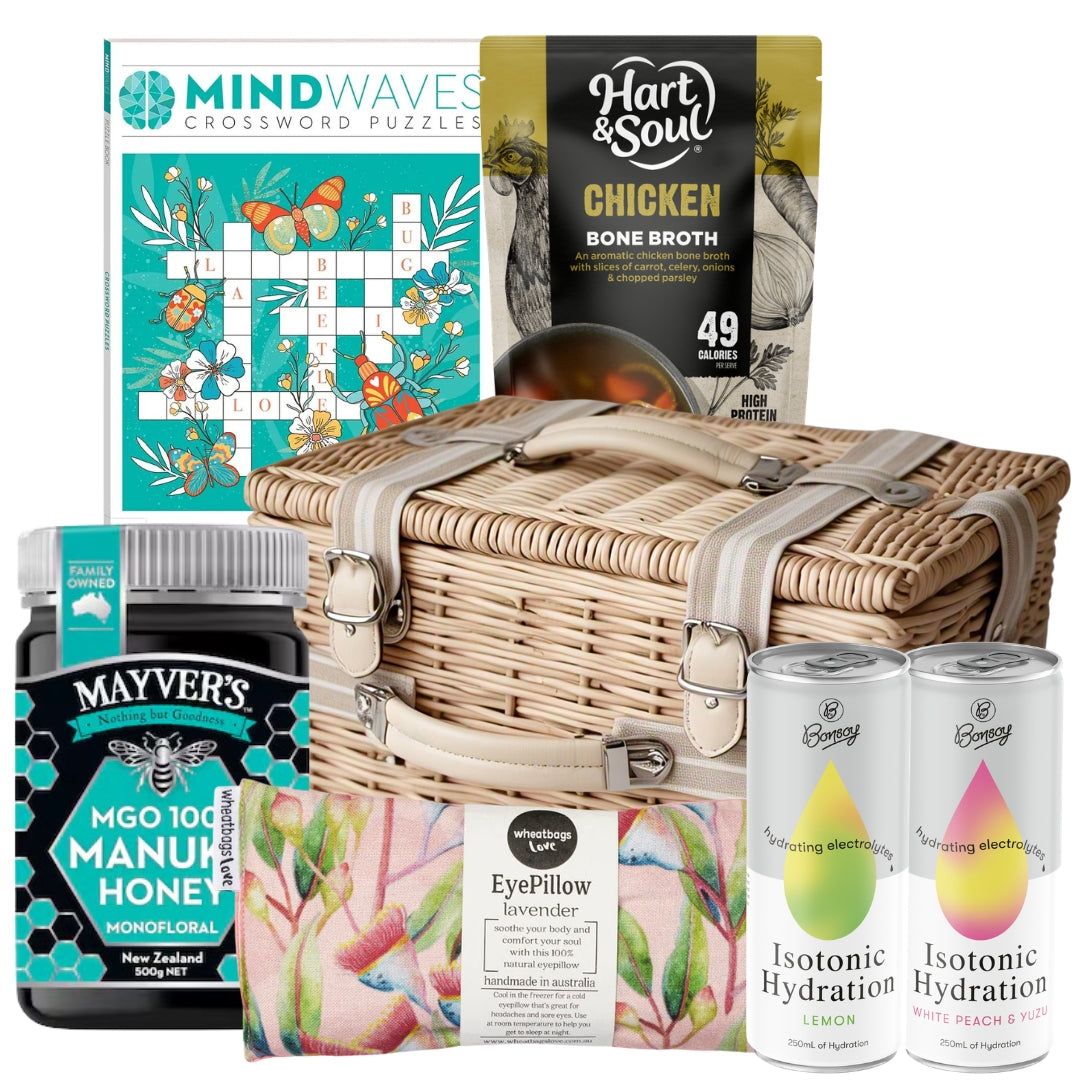 Get well soon gift basket featuring a crossword puzzle book, lavender wheat bag, chicken broth soup, electrolyte drinks, and Manuka honey