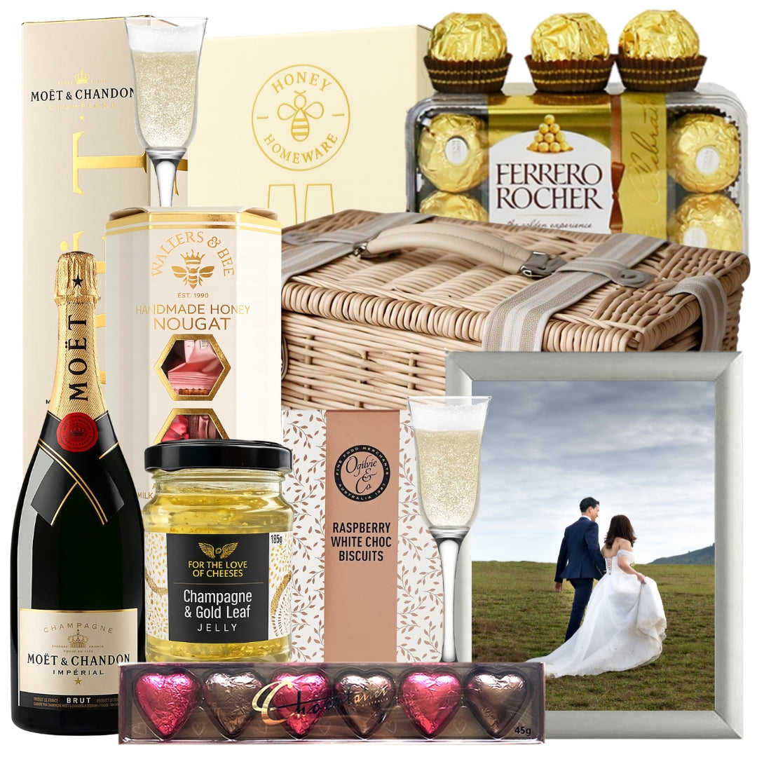 Champagne wedding gift basket featuring Moët Brut Impérial Champagne, champagne flutes, chocolates, champagne jelly, a photo frame, and gourmet treats