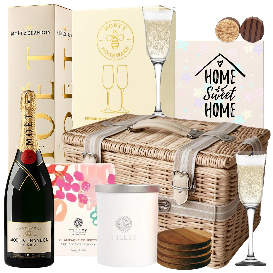 Champagne housewarming gift basket featuring Moët Brut Impérial Champagne, champagne flutes, a scented candle, wooden coasters, and chocolates